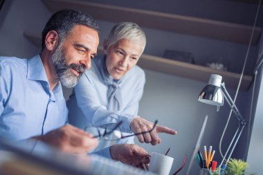 Dizüstü bilgisayar kullanarak ve yeni fikirler birlikte ofiste çalışırken tartışırken iş adamları