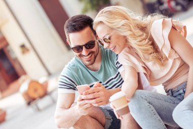 Genç oturan ve kullanma smartphone gündüz çift.