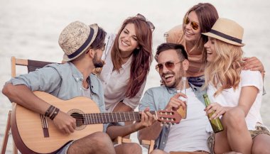Bir grup genç insan yaz sahilde gitar çalmak