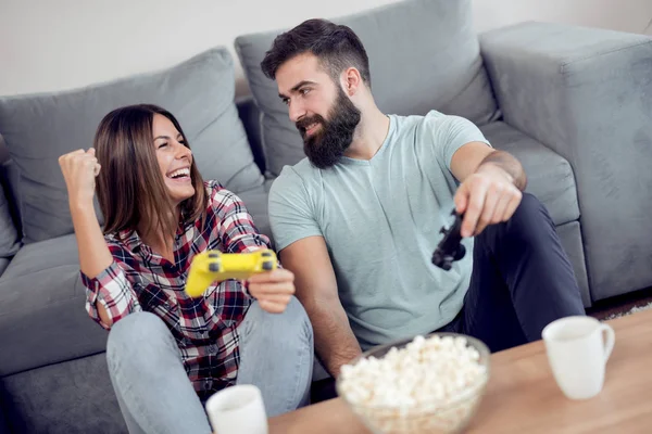 couple sitting together in living room with popcorn and playing video game