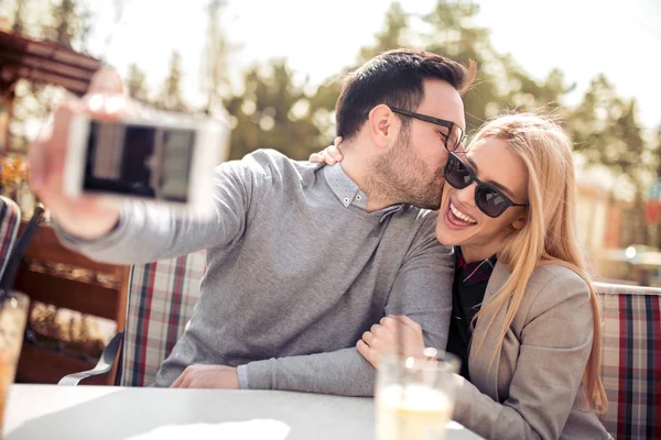 Man and woman dating in cafe and making selfie at smartphone