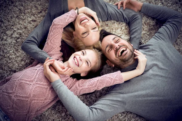 カメラ目線し ながら自宅の床に横になっている笑顔の若い家族の平面図 — ストック写真