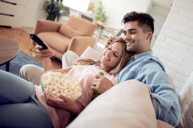 Genç çift dairelerinde rahatlatıcı, kanepede yatan, film izlerken ve patlamış mısır yemek.