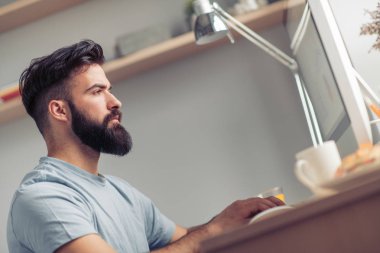 Adam bilgisayar kullanıyor ve ev ofis.