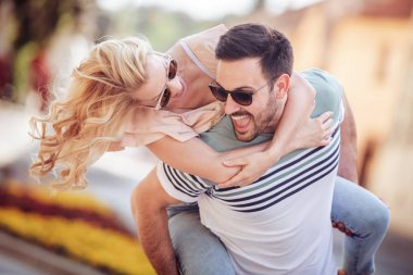 Onun kız arkadaşı uzanmış silah tutarken piggybacking neşeli genç adam.