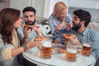 Bir grup genç insan birlikte eğlenirken pizza yemek.