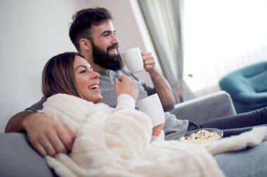 Genç çift dairelerinde rahatlatıcı, kanepede oturan, film izlerken ve patlamış mısır yemek. 
