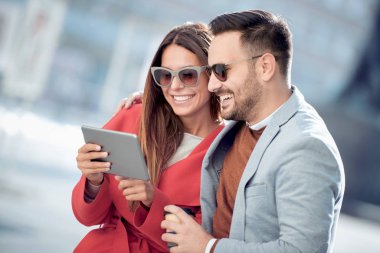 Açık havada eğleniyor ve gülümseyerek, tablet üzerinde seyir mutlu genç Çift.