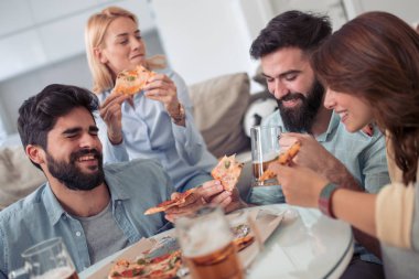 Bir grup genç insan birlikte eğlenirken pizza yemek.