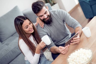 Romantik Çift tablet bilgisayar kullanarak. Genç çift evde beraber sörf.
