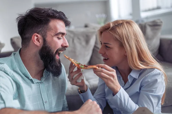 Happy young couple enjoying pizza at home.People,love,food and home concept.