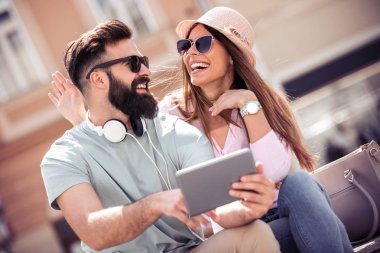 Tablet kullanma ve sokakta müzik dinlemek genç çift portresi.