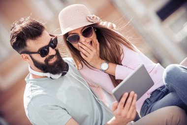 Tablet kullanma ve sokakta müzik dinlemek genç çift portresi.