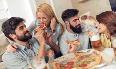 Bir grup genç insan birlikte eğlenirken pizza yemek.