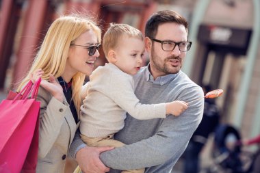 Mutlu aile alışveriş torbaları ve sokakta yürürken lolipop. Satılık, tüketim ve Aile kavramı 