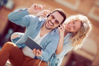 Dijital tablet kullanma ve sokakta müzik dinlemek bir çift portresi.