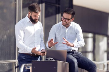 İki işadamı çalışma proje hakkında açık, konuşurken bir dizüstü bilgisayar kullanarak.