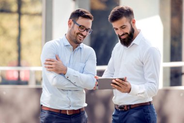 Genç yakışıklı işadamları proje açık havada dijital tablet üzerinde tartışıyor.