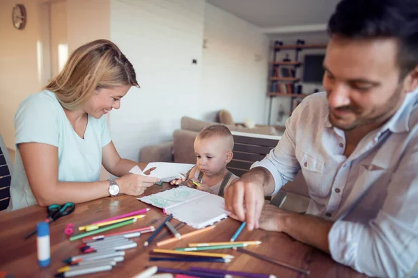 Mom and dad drawing with their son.They are having fun in their living room.