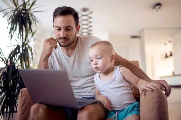 Family, fatherhood, technology and people concept - happy father and little son with laptop.