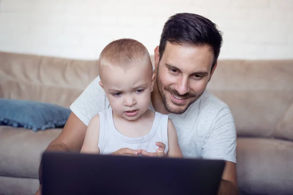 Family, fatherhood, technology and people concept - happy father and little son with laptop.