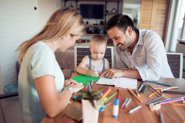 Mom and dad drawing with their son.They are having fun in their living room.