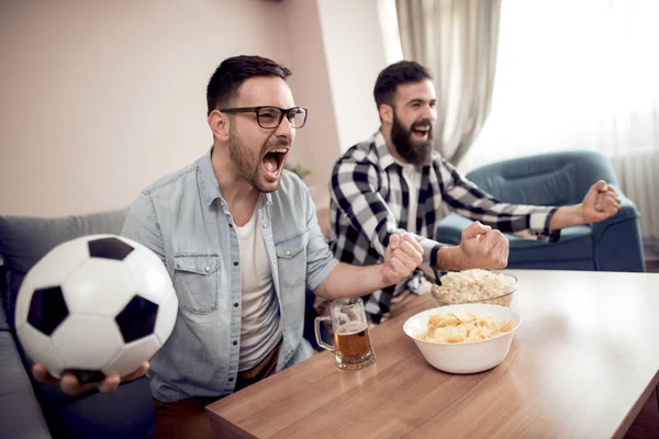 Friendship,sport, people and entertainment concept - happy male friends watching soccer on tv at home.