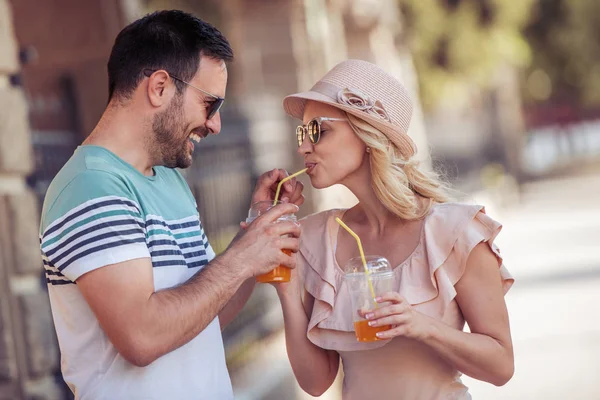 Bankta oturup meyve suyu içen gülümseyen çiftin portresi..