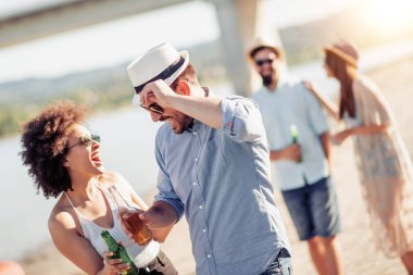 Eğleniyor ve sahilde bira içme arkadaşlar. Yaz tatili, insanlar, eğlence ve tatil kavramı.