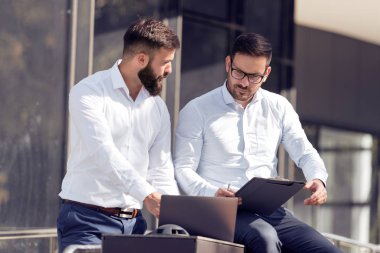 İki işadamları çalışma proje hakkında açık, konuşurken bir bilgi paylaşımı için bir dizüstü bilgisayar kullanarak.