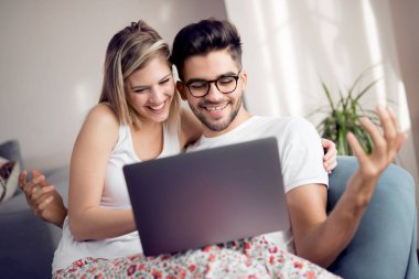 Birlikte laptop evde oturma odasında kullanarak kanepede rahatlatıcı mutlu çift.