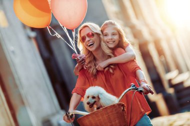 Anne ve kızı şehirde, eğleniyor Bisiklete binmek. 