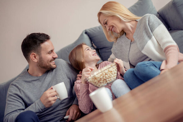 Молодая семья вместе смотрит телевизор дома и веселится вместе
.