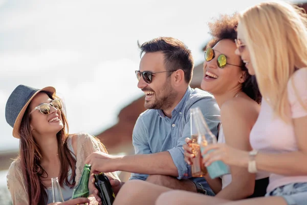 Eğleniyor ve sahilde bira içme arkadaşlar. Yaz tatili, insanlar, eğlence ve tatil kavramı.