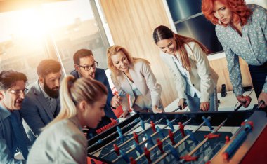 Modern ofis masa futbolu oynayan gülümseyen iş arkadaşları.