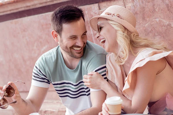 Mutlu çift turist tatile çeşme yanındaki şehir meydanında oturuyor.