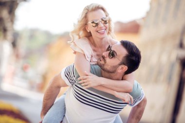 Genç adam bir kız şehrin sokak sırtında taşıyan.