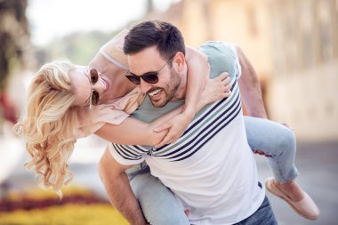 Genç adam bir kız şehrin sokak sırtında taşıyan.