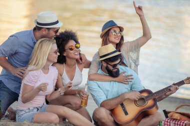 Arkadaşlar eğlenmeye sahilde gitar ile neşeli grup.