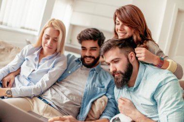 Birlikte kanepede oturan ve eğlenceli izlerken arkadaşlar video üstünde laptop.