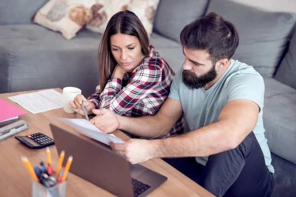 Genç karı koca beraber evrak işlerini yapmak, yaptıkları harcamaların hesaplama, faturaları yönetme, dizüstü bilgisayar kullanarak.