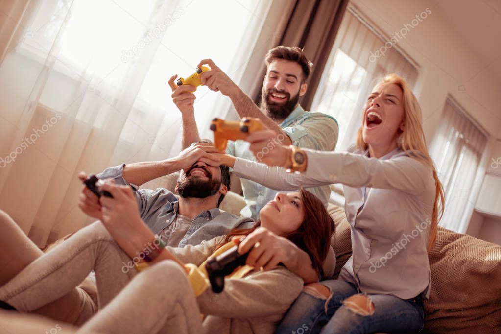 Friends having fun at home, playing video games.
