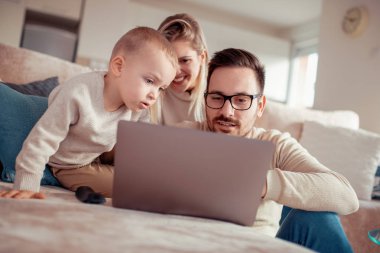 Gülümseyen veliler ve küçük oğlu dizüstü evde kullanma.