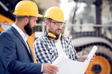 Şantiye meslektaşı ile güneşli günde tartışırken mühendisi. 