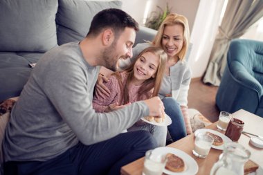 Üç ev onların oturma odasında sabahları kahvaltı sahip aile gülümseyen 
