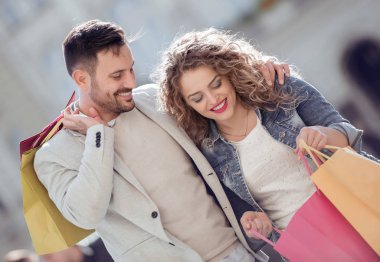 Alışveriş torbalarıyla mutlu bir çiftin portresi. Satış, tüketim ve insan konsepti.