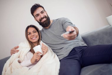 Onların evinde rahatlatıcı, kanepede oturan, bir film seyrederken genç çift.