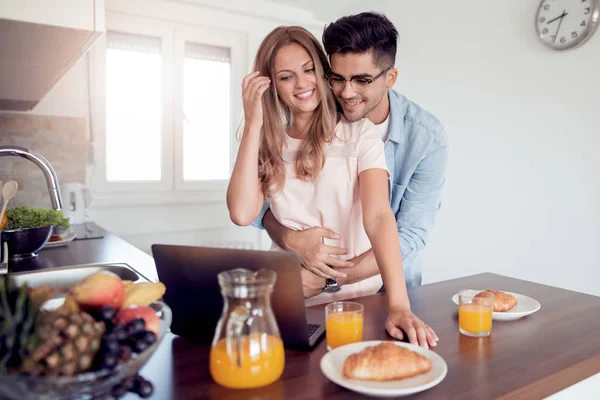 People, communication, technology and leisure. Young cute couple having breakfast while also browsing the laptop for more financial records.