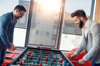 Modern ofis masa futbolu oynayan gülümseyen iş arkadaşları.