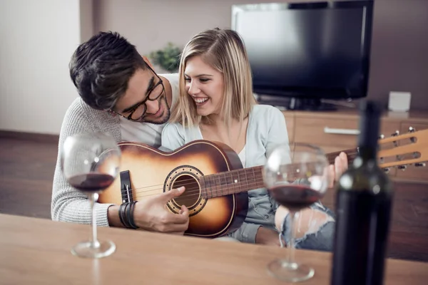 Genç ve güzel bir çift evde dinleniyor ve gitar çalıyor..
